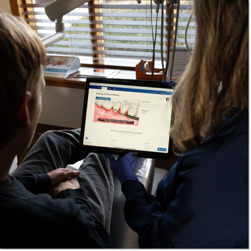 Two people looking at a screen that has a picture demonstrating dental cleaning